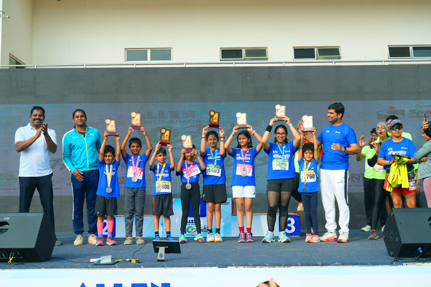 Young athletes holding trophies on stage